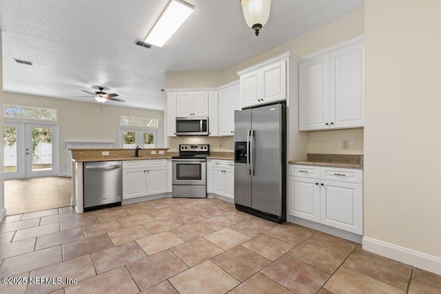 kitchen with appliances with stainless steel finishes, white cabinets, french doors, kitchen peninsula, and ceiling fan