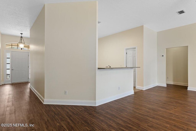 unfurnished living room with vaulted ceiling, dark hardwood / wood-style floors, and a textured ceiling