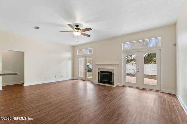 unfurnished living room featuring ceiling fan, a textured ceiling, dark hardwood / wood-style floors, and french doors