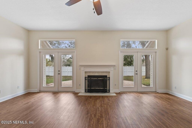 unfurnished living room featuring hardwood / wood-style floors, french doors, a high ceiling, a premium fireplace, and ceiling fan