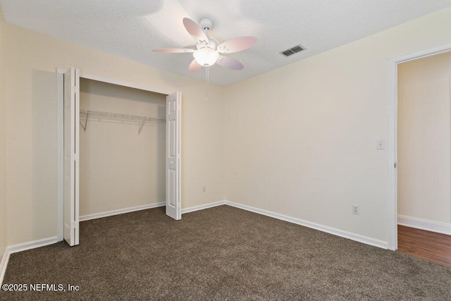 unfurnished bedroom with a closet, ceiling fan, dark colored carpet, and a textured ceiling