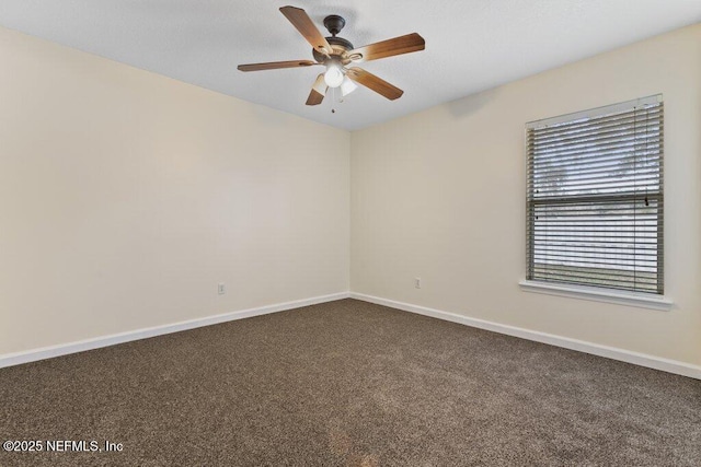 empty room with ceiling fan and dark colored carpet