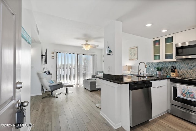 kitchen featuring kitchen peninsula, sink, white cabinetry, light hardwood / wood-style flooring, and appliances with stainless steel finishes