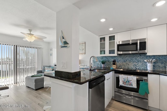 kitchen with white cabinets, stainless steel appliances, light hardwood / wood-style floors, sink, and kitchen peninsula