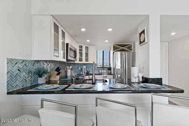 kitchen with tasteful backsplash, sink, stainless steel appliances, and white cabinetry