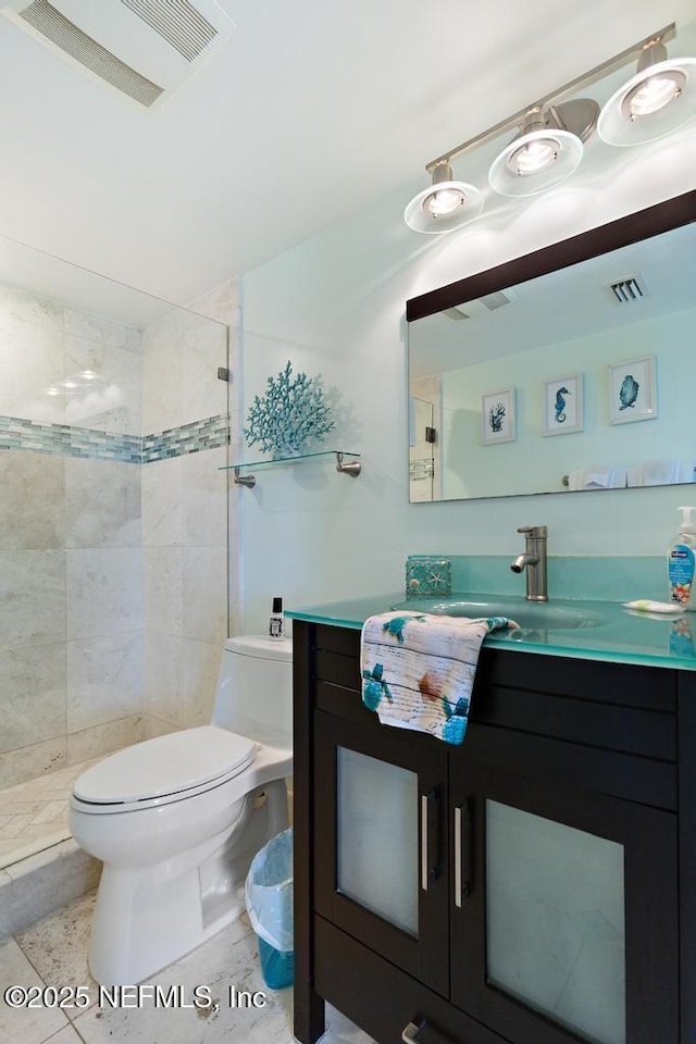 bathroom featuring toilet, vanity, tile patterned floors, and tiled shower