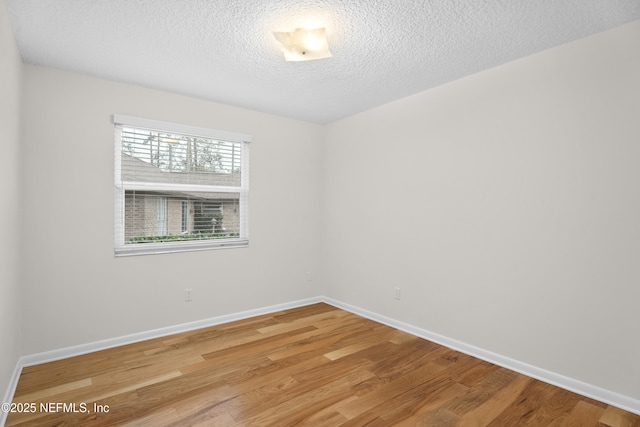 spare room with a textured ceiling and hardwood / wood-style flooring