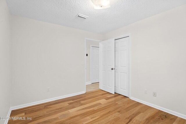 unfurnished bedroom with light hardwood / wood-style flooring and a textured ceiling