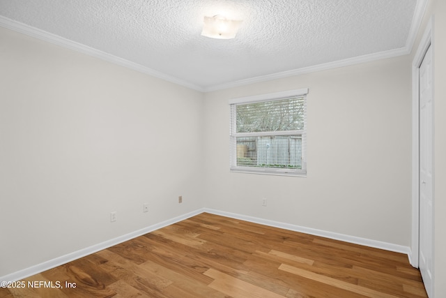 spare room with hardwood / wood-style floors, a textured ceiling, and crown molding