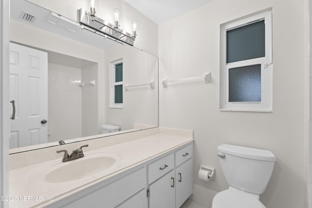 bathroom featuring walk in shower, vanity, and toilet