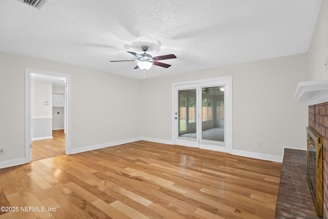 unfurnished living room with a fireplace, a textured ceiling, light hardwood / wood-style flooring, and ceiling fan