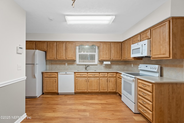 kitchen with backsplash, light wood-type flooring, white appliances, and sink