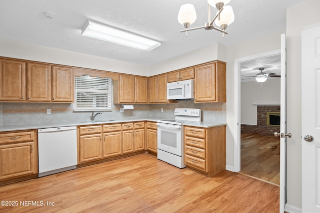 kitchen with tasteful backsplash, ceiling fan with notable chandelier, white appliances, sink, and pendant lighting