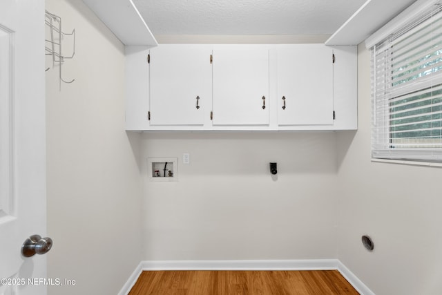 clothes washing area featuring hardwood / wood-style floors, electric dryer hookup, cabinets, washer hookup, and a textured ceiling