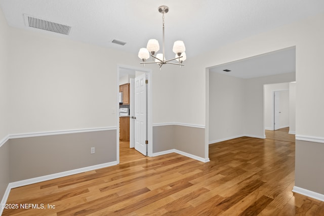 empty room featuring hardwood / wood-style floors and a notable chandelier