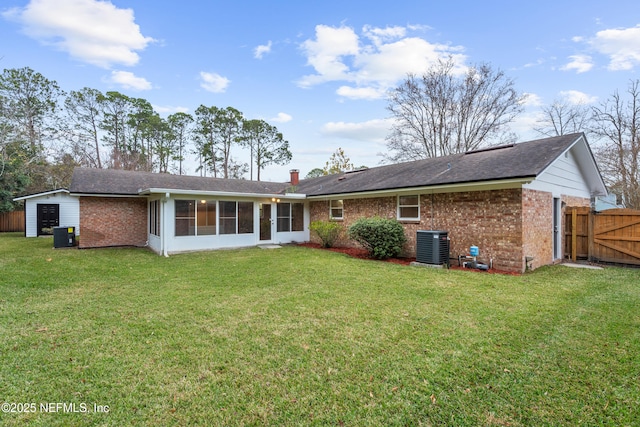 rear view of house featuring a lawn, a sunroom, and central air condition unit