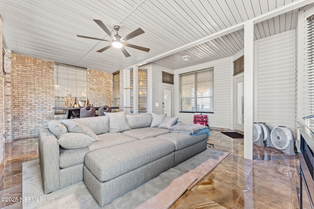 living room featuring ceiling fan and brick wall