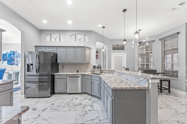 kitchen featuring sink, hanging light fixtures, stainless steel fridge, gray cabinets, and backsplash