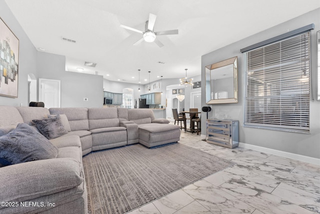 living room with ceiling fan with notable chandelier