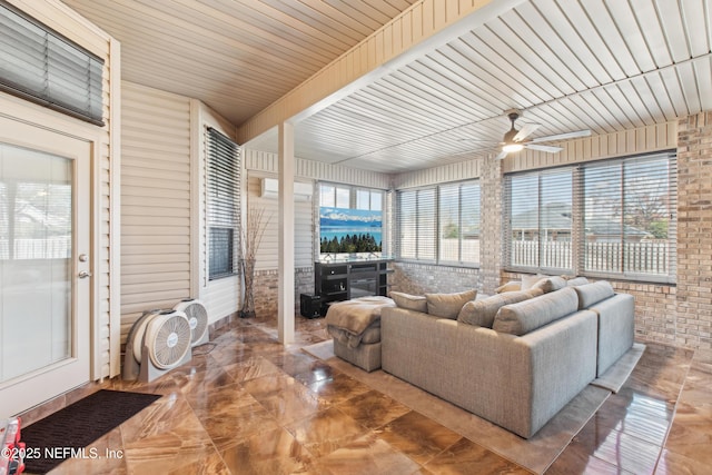 living room featuring ceiling fan and brick wall