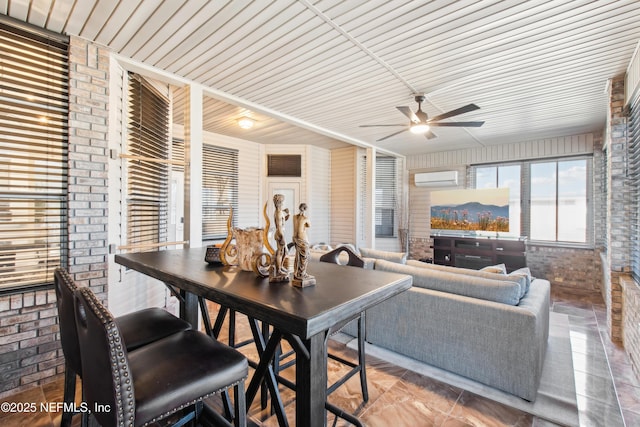 interior space with ceiling fan, brick wall, and a wall mounted AC