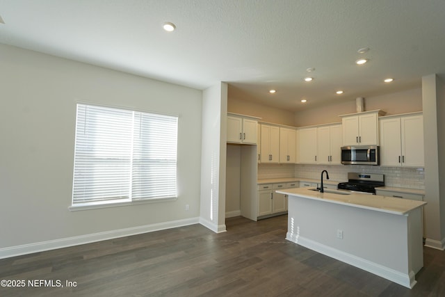 kitchen featuring white cabinets, a center island with sink, stainless steel appliances, decorative backsplash, and sink