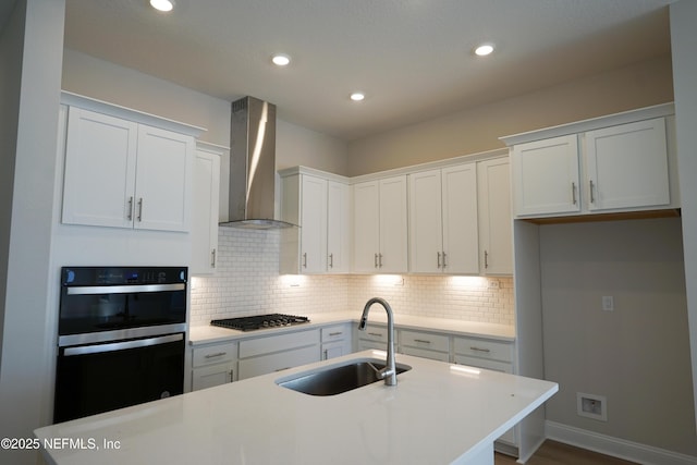 kitchen with white cabinets, wall chimney exhaust hood, and sink