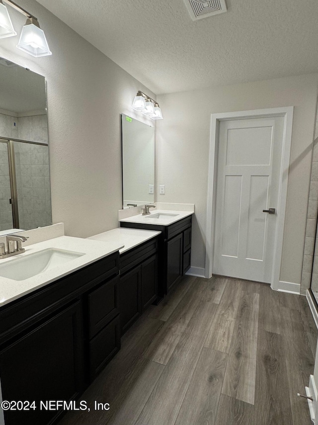 bathroom with vanity, an enclosed shower, wood-type flooring, and a textured ceiling