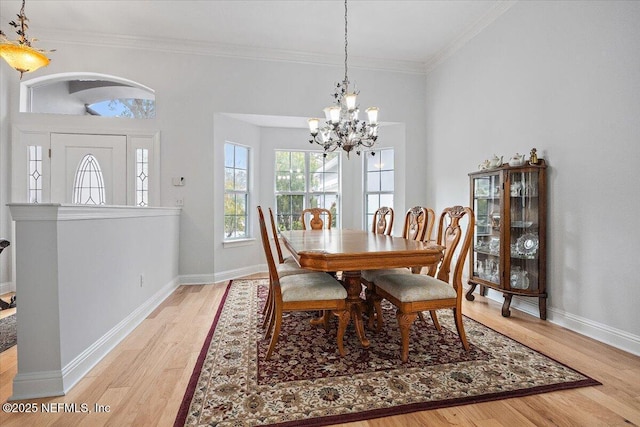 dining area featuring crown molding, an inviting chandelier, and light hardwood / wood-style flooring