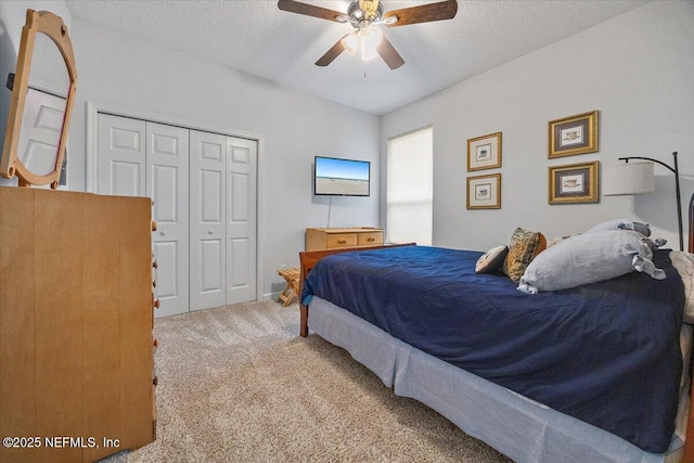 bedroom featuring ceiling fan, light colored carpet, a closet, and a textured ceiling