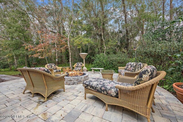 view of patio with an outdoor living space with a fire pit