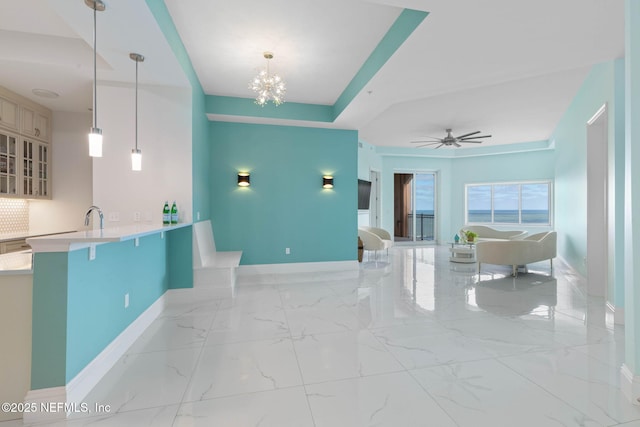 interior space with ceiling fan with notable chandelier, sink, hanging light fixtures, a kitchen bar, and kitchen peninsula