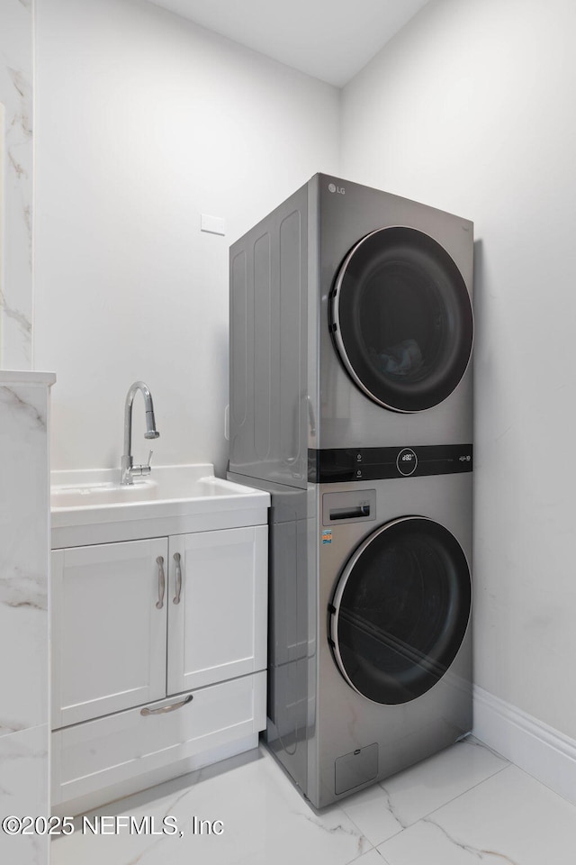 clothes washing area featuring sink, cabinets, and stacked washer / drying machine