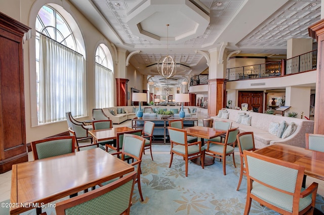 interior space with coffered ceiling, a high ceiling, decorative columns, crown molding, and light tile patterned flooring