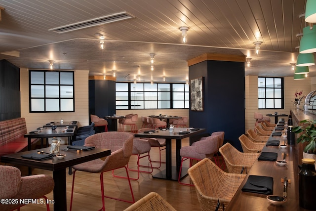 dining space with hardwood / wood-style flooring, wood walls, and wooden ceiling