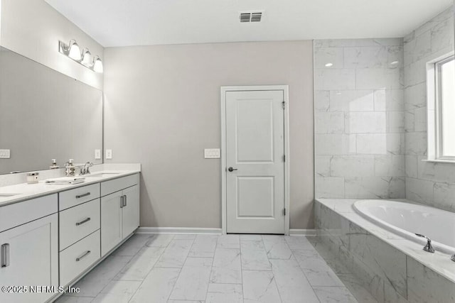 bathroom featuring tiled tub and vanity