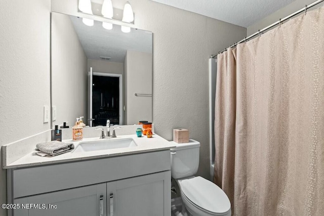 bathroom with toilet, vanity, and a textured ceiling