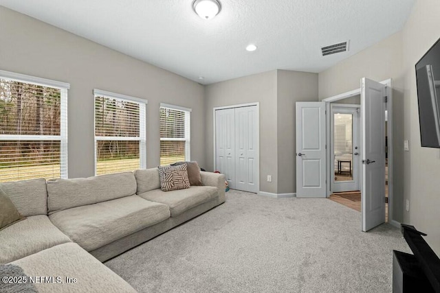 living room with light carpet, a textured ceiling, and a healthy amount of sunlight