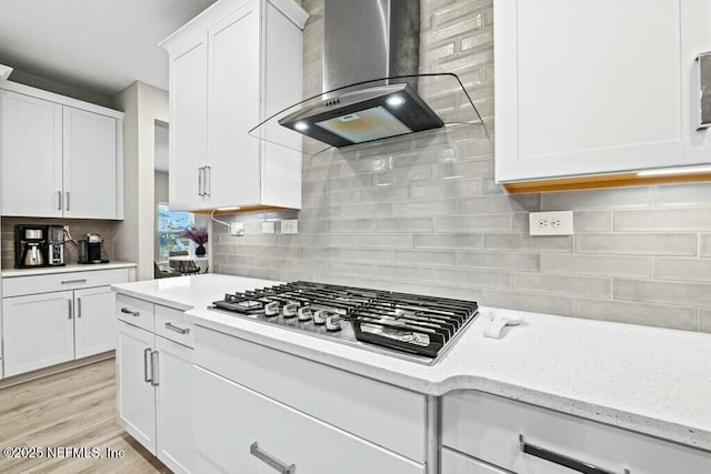 kitchen featuring extractor fan, decorative backsplash, stainless steel gas cooktop, light stone countertops, and white cabinets