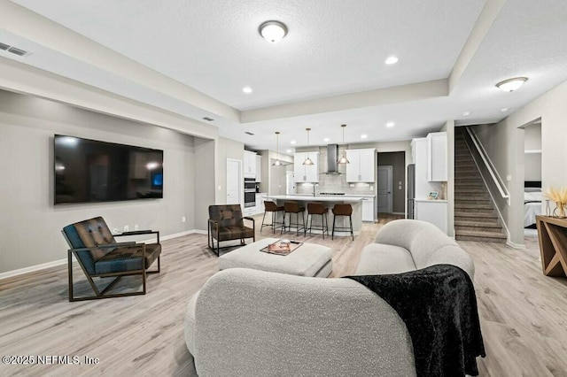 living room with a raised ceiling and light hardwood / wood-style floors