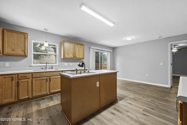 kitchen featuring hardwood / wood-style flooring, sink, hanging light fixtures, and a kitchen island with sink