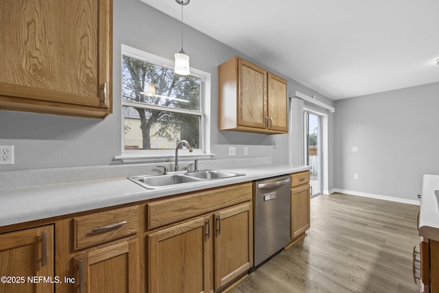 kitchen with light hardwood / wood-style flooring, decorative light fixtures, stainless steel dishwasher, and sink