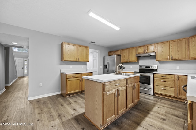 kitchen featuring appliances with stainless steel finishes, hardwood / wood-style flooring, a kitchen island with sink, and sink