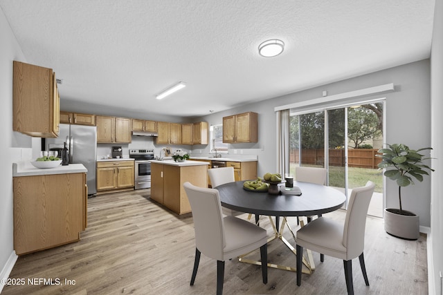 dining room featuring a textured ceiling, light wood-type flooring, and sink