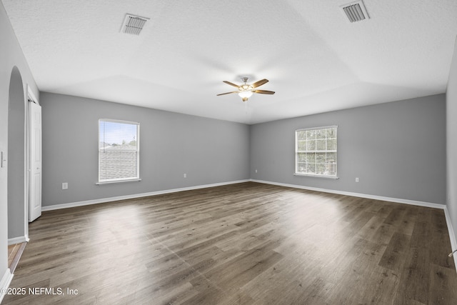 unfurnished room with a textured ceiling, plenty of natural light, ceiling fan, and dark wood-type flooring