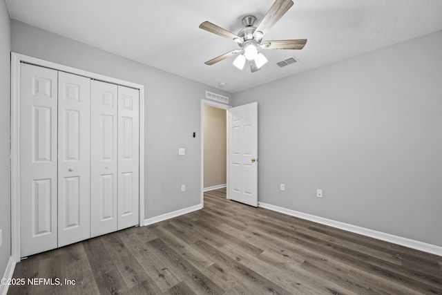 unfurnished bedroom with ceiling fan, dark hardwood / wood-style floors, and a closet