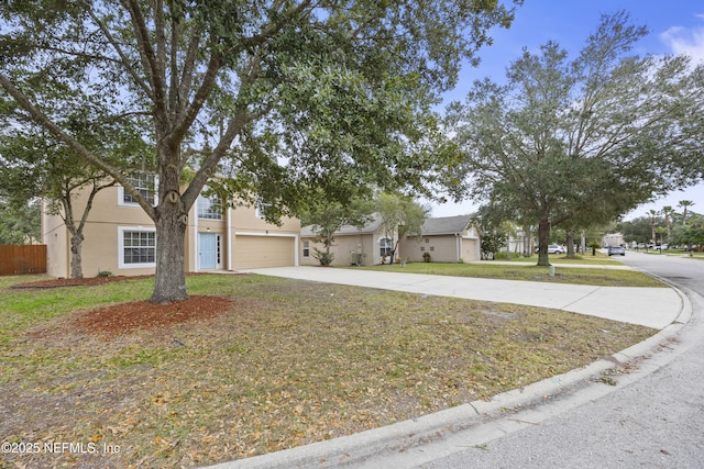 view of property hidden behind natural elements featuring a garage and a front yard