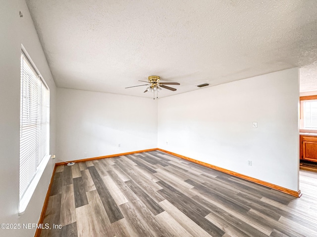 empty room with a healthy amount of sunlight, ceiling fan, and a textured ceiling