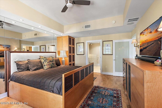 bedroom featuring light wood-type flooring, ensuite bathroom, and ceiling fan