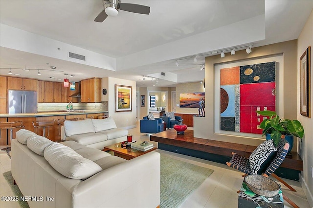 living room with ceiling fan, sink, and light tile patterned floors